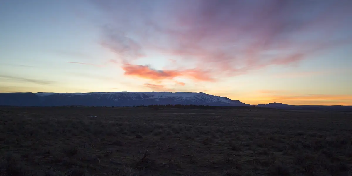 Pink sunrise clouds over a dark sagebrush ridge near Steens Mountain